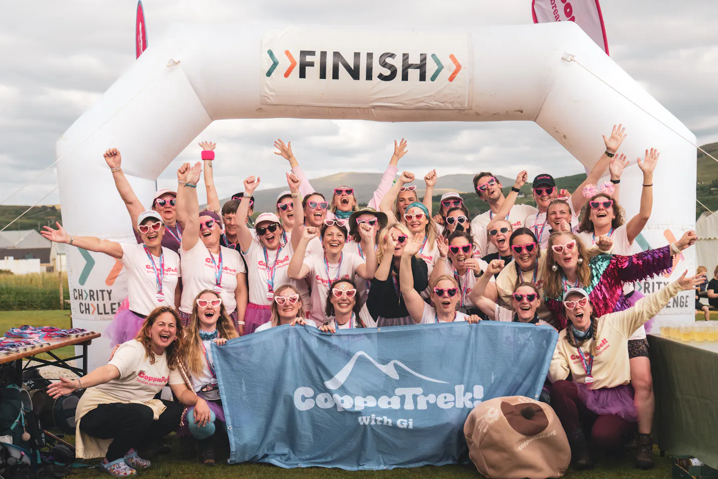 A large group of trekkers celebrating in front of the finish line.
