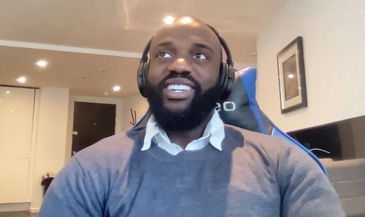 Smiling man sits in front of computer