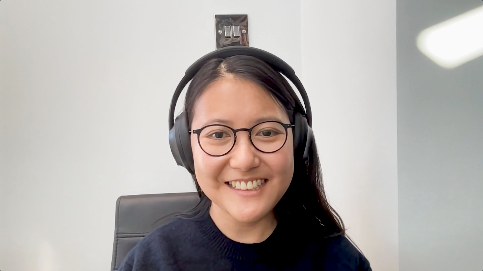 Woman wearing glasses smiles in front of computer
