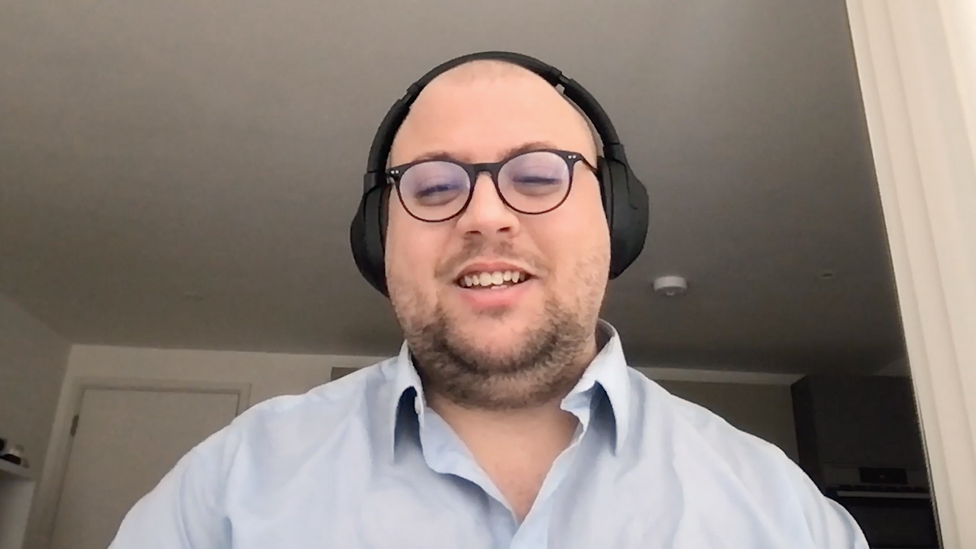 Smiling man with glasses sits in front of computer