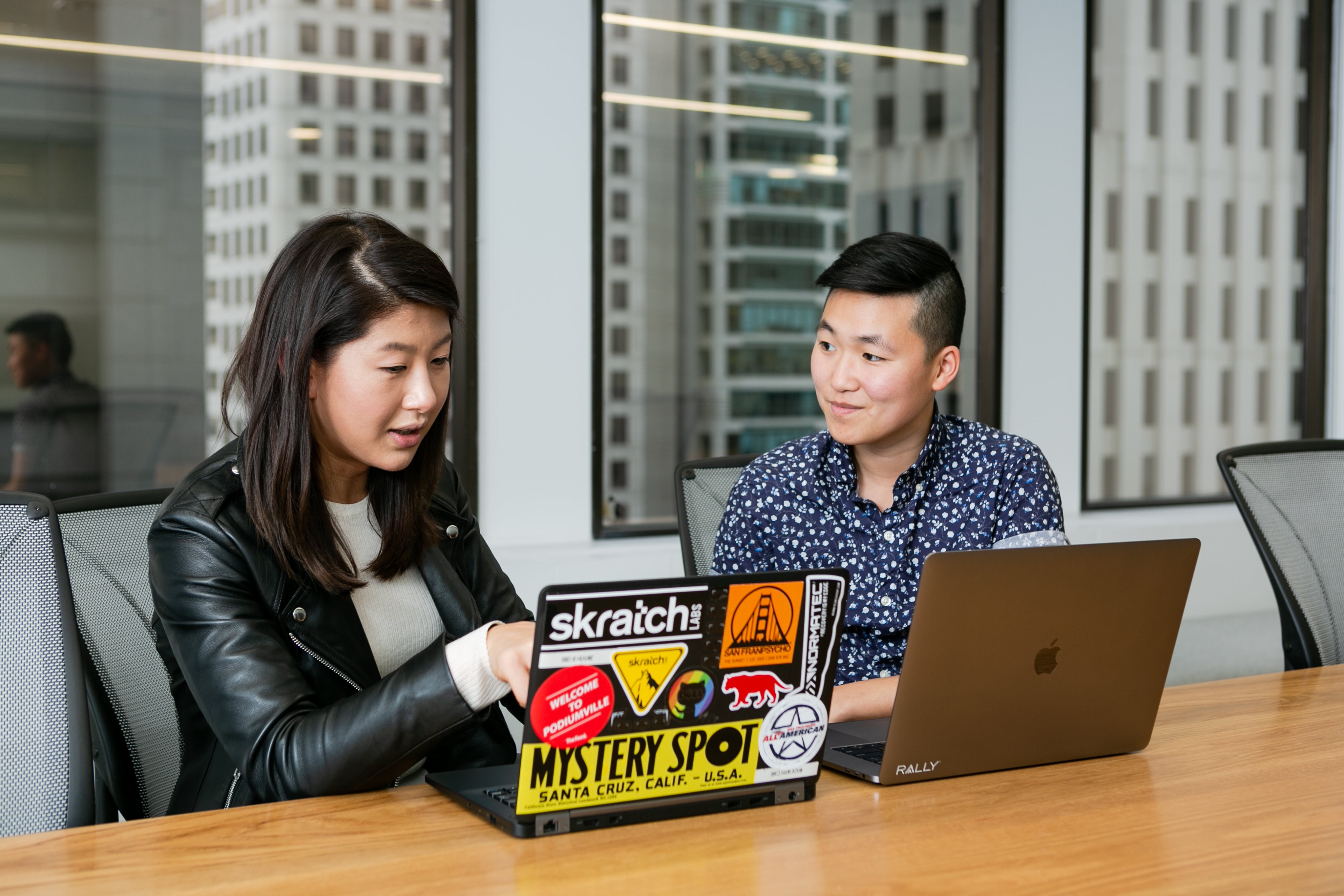 Two people sitting in a conference room looking at laptops