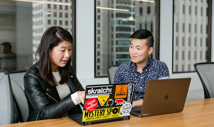 Two people sitting in a conference room looking at laptops