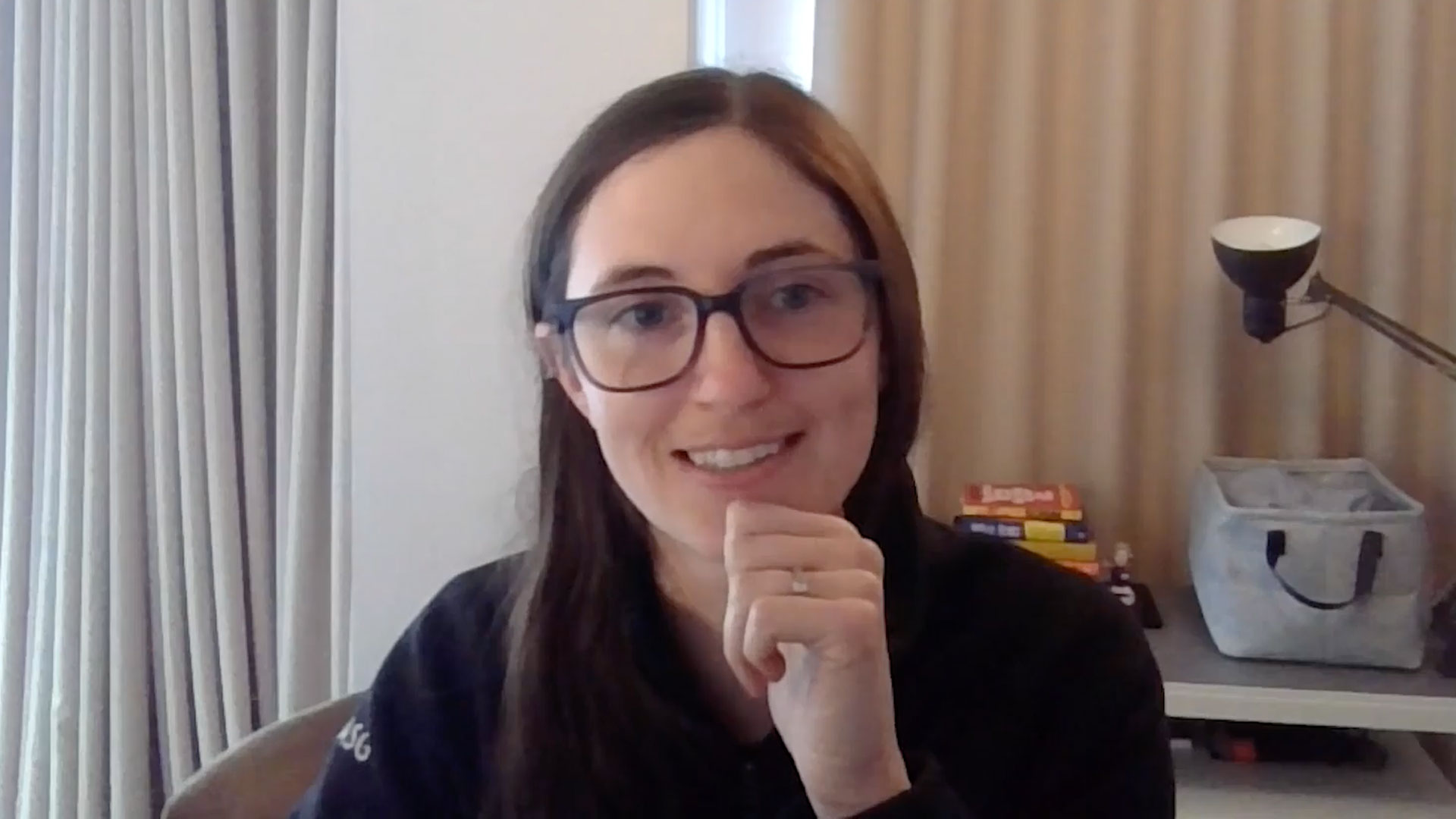 Smiling woman with glasses sits in front of computer