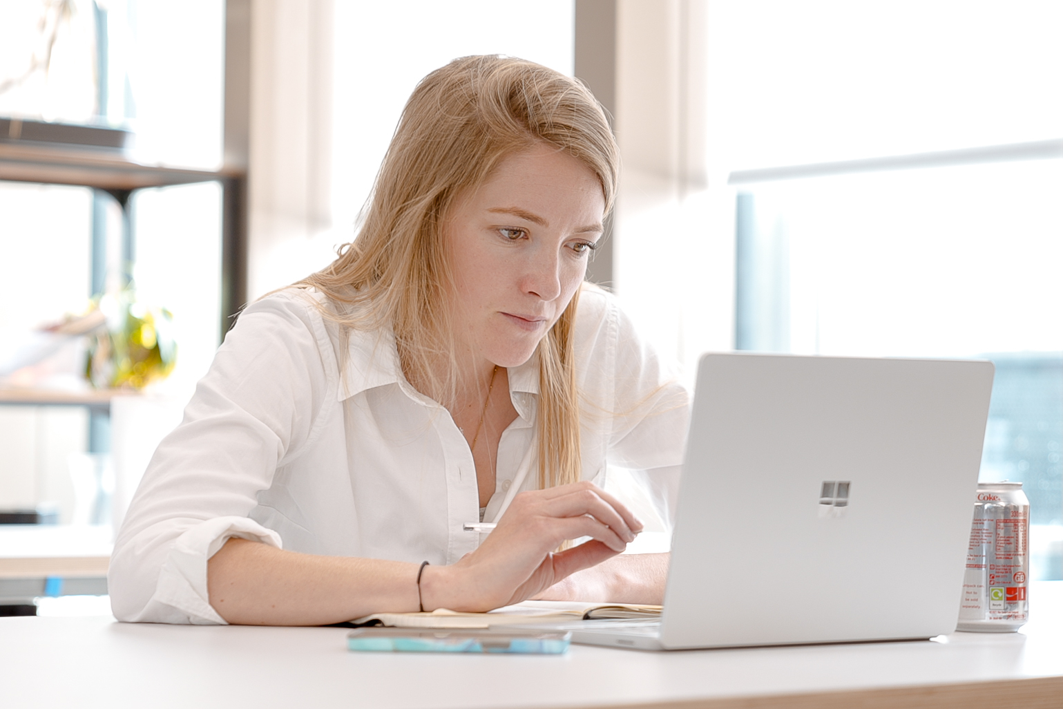 Cover of A woman sitting at a desk in a brightly lit office looking at a laptop article