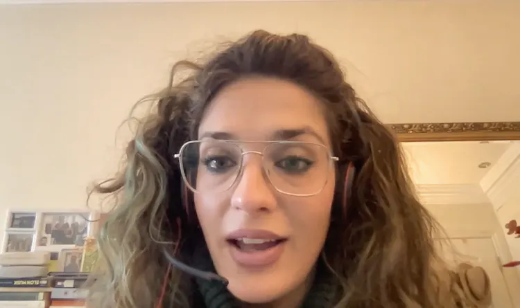 Woman with glasses sits in front of computer
