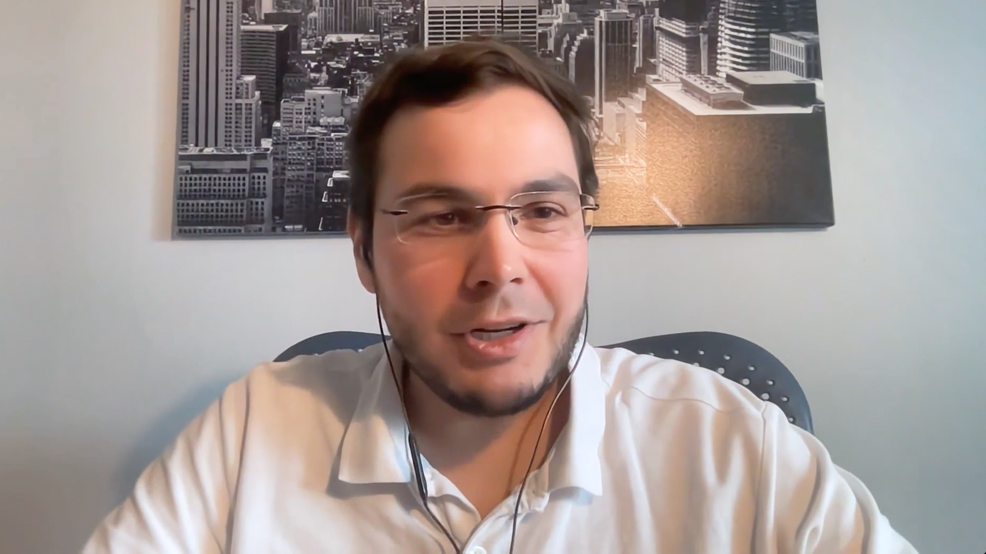 Man with glasses smiles at computer