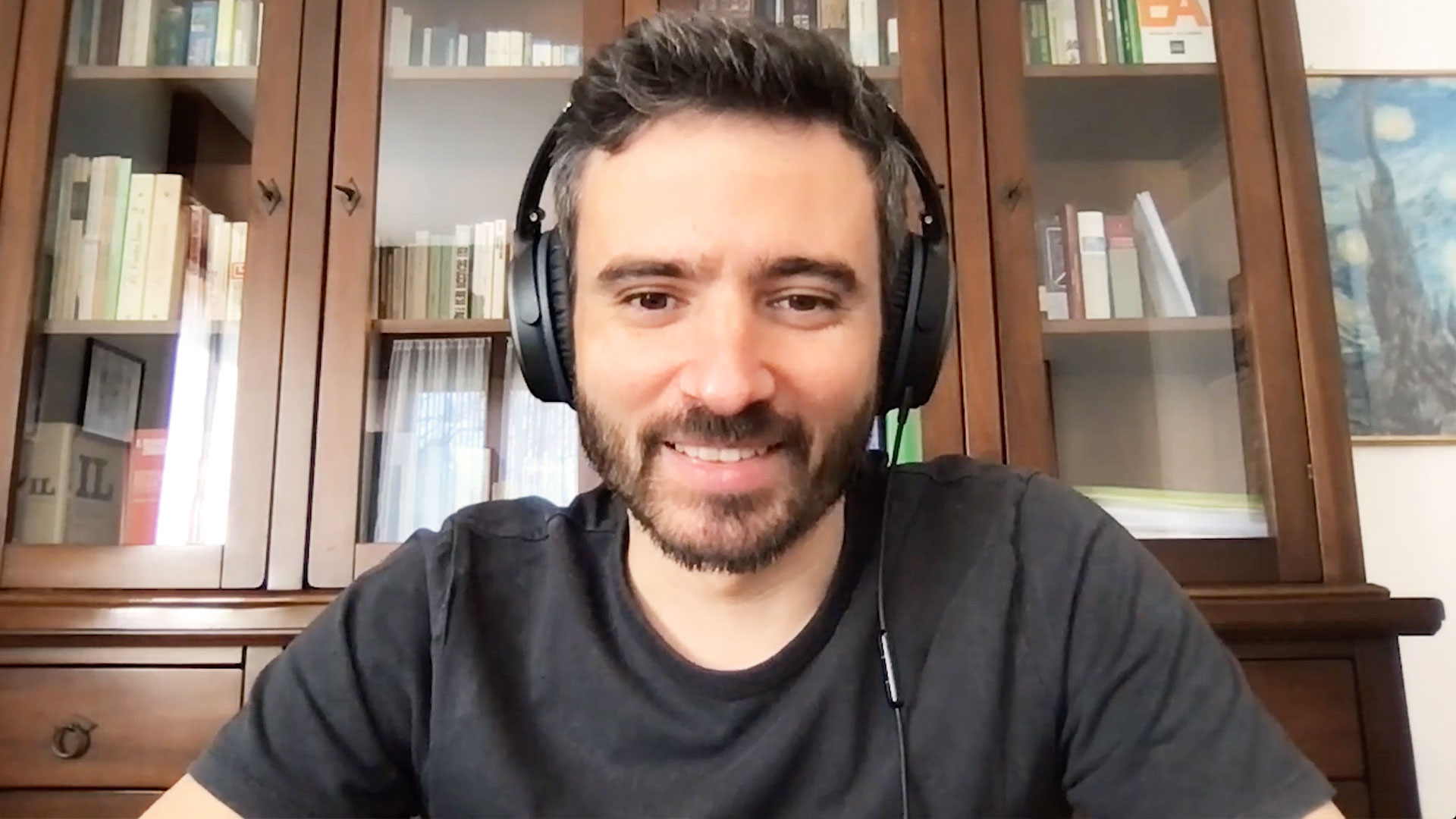 Smiling man wearing headphones sits at computer