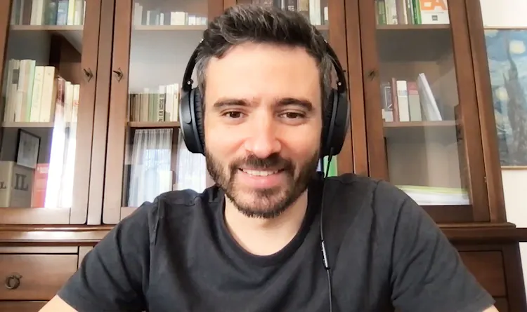 Smiling man wearing headphones sits at computer