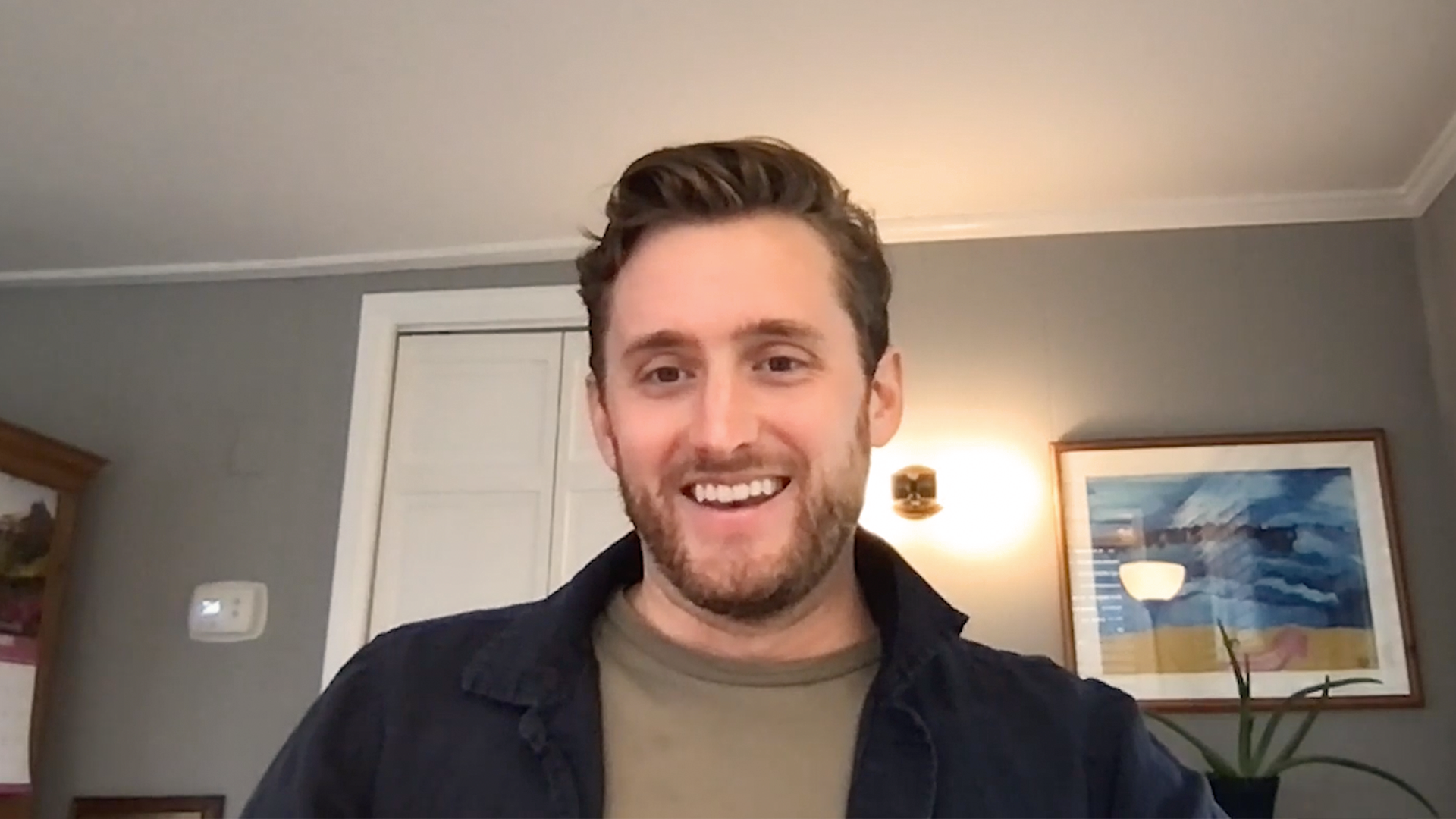 Smiling man sits in front of computer