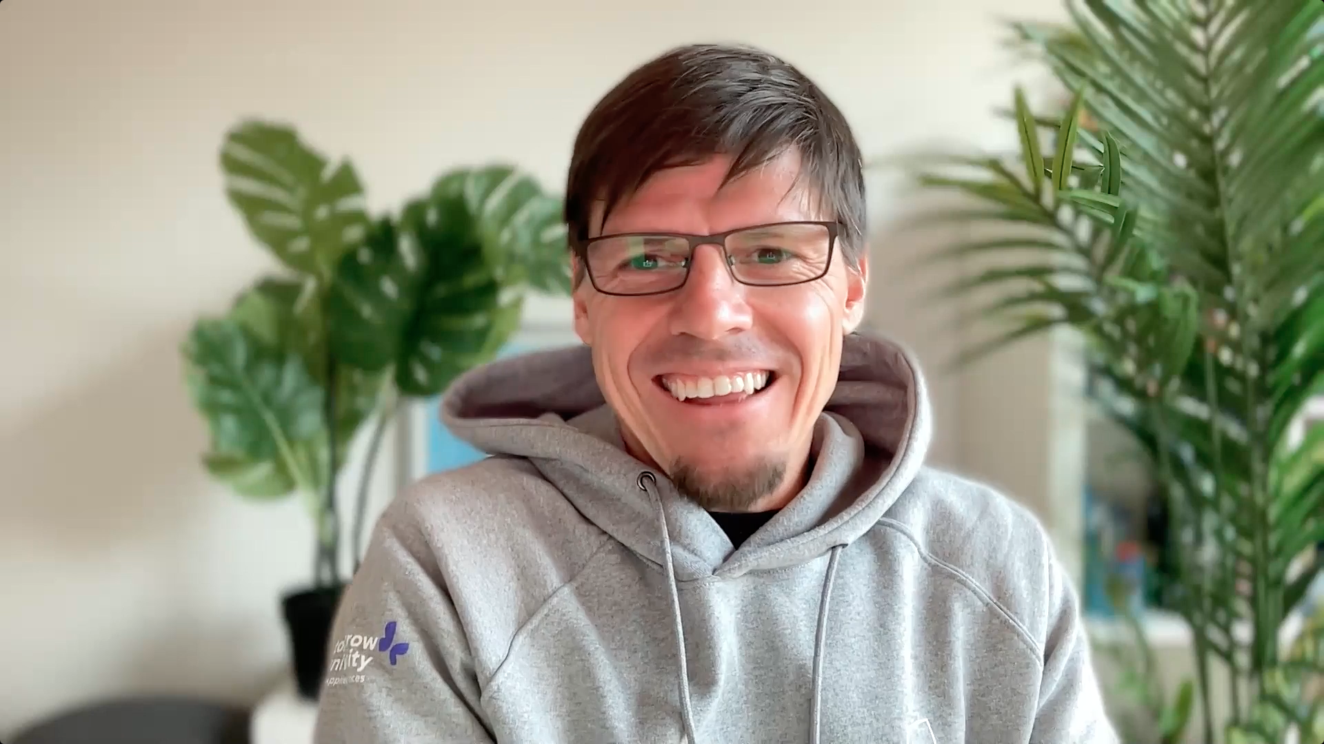 Smiling man with glasses sits in front of computer