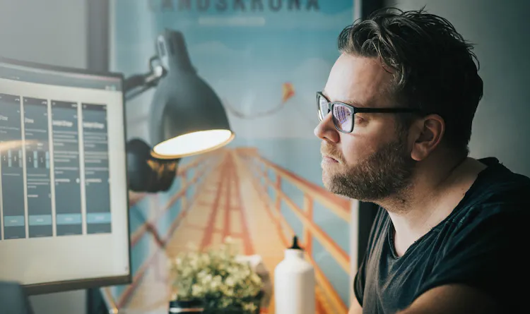 Cover of Man sitting at a desk looking at a monitor with several preview images on it article