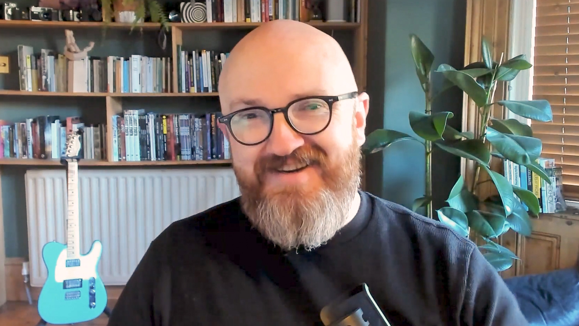 Man with glasses smiles in front of computer