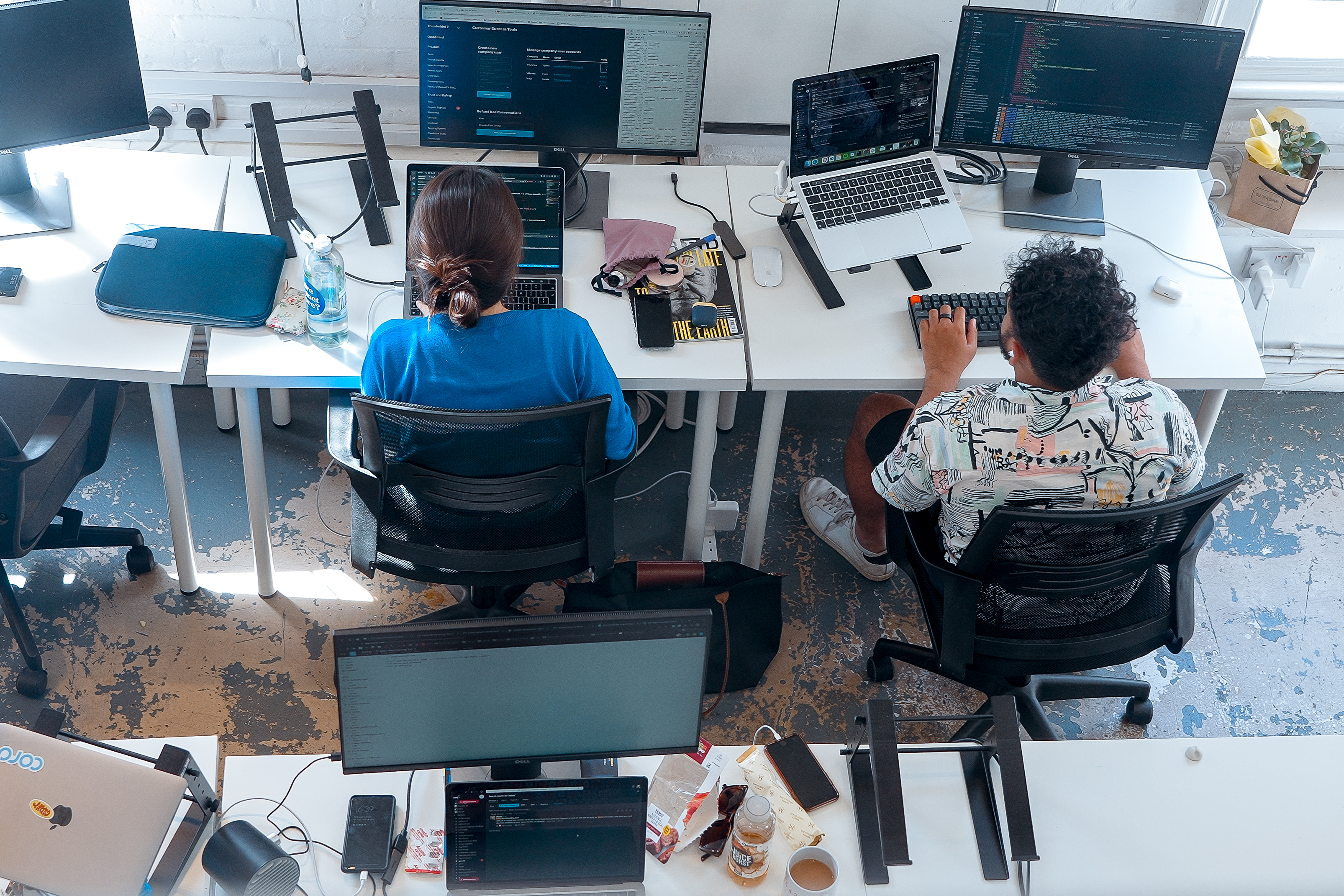 Cover of Two people sitting at a desk working on laptops are seen from above article