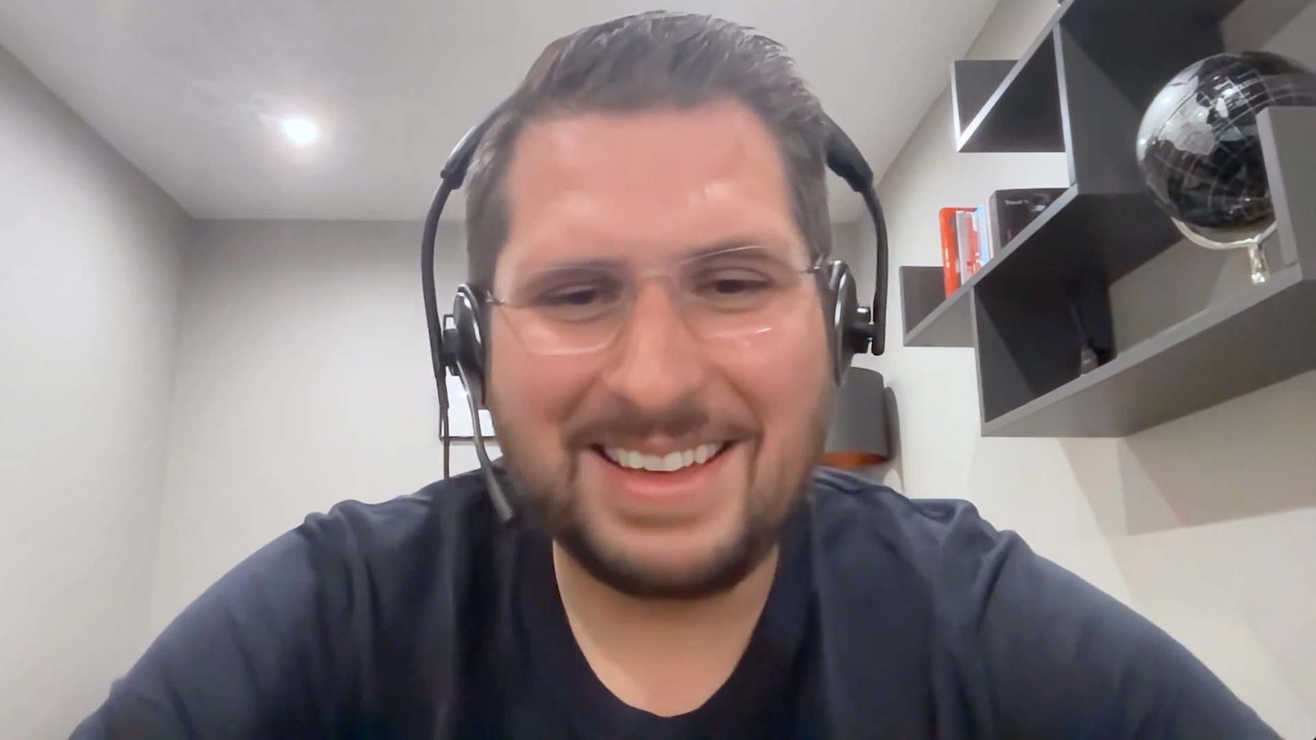 Man with glasses and headphones smiles in front of computer