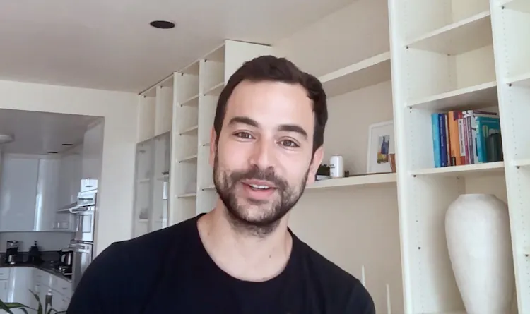 Smiling man stands in front of desk