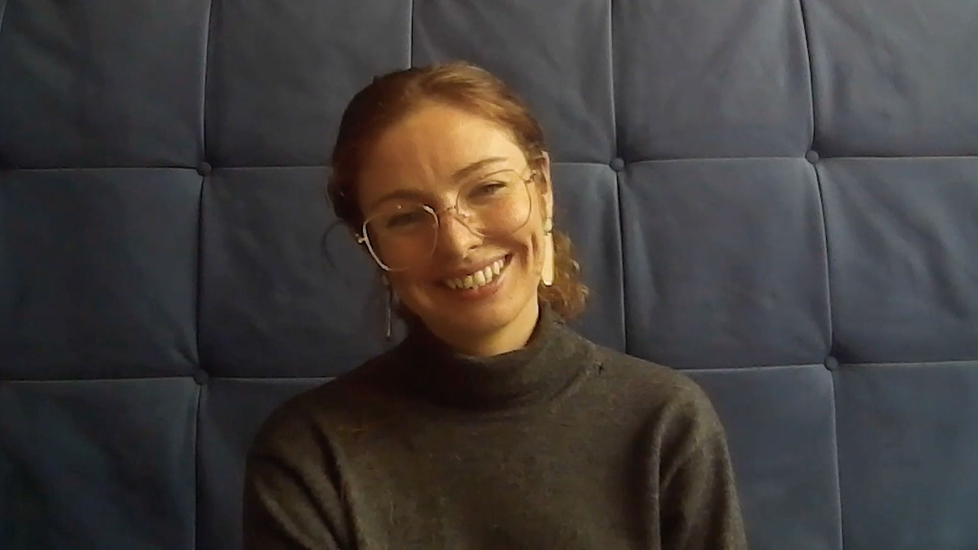 Smiling woman with glasses sits at conmputer