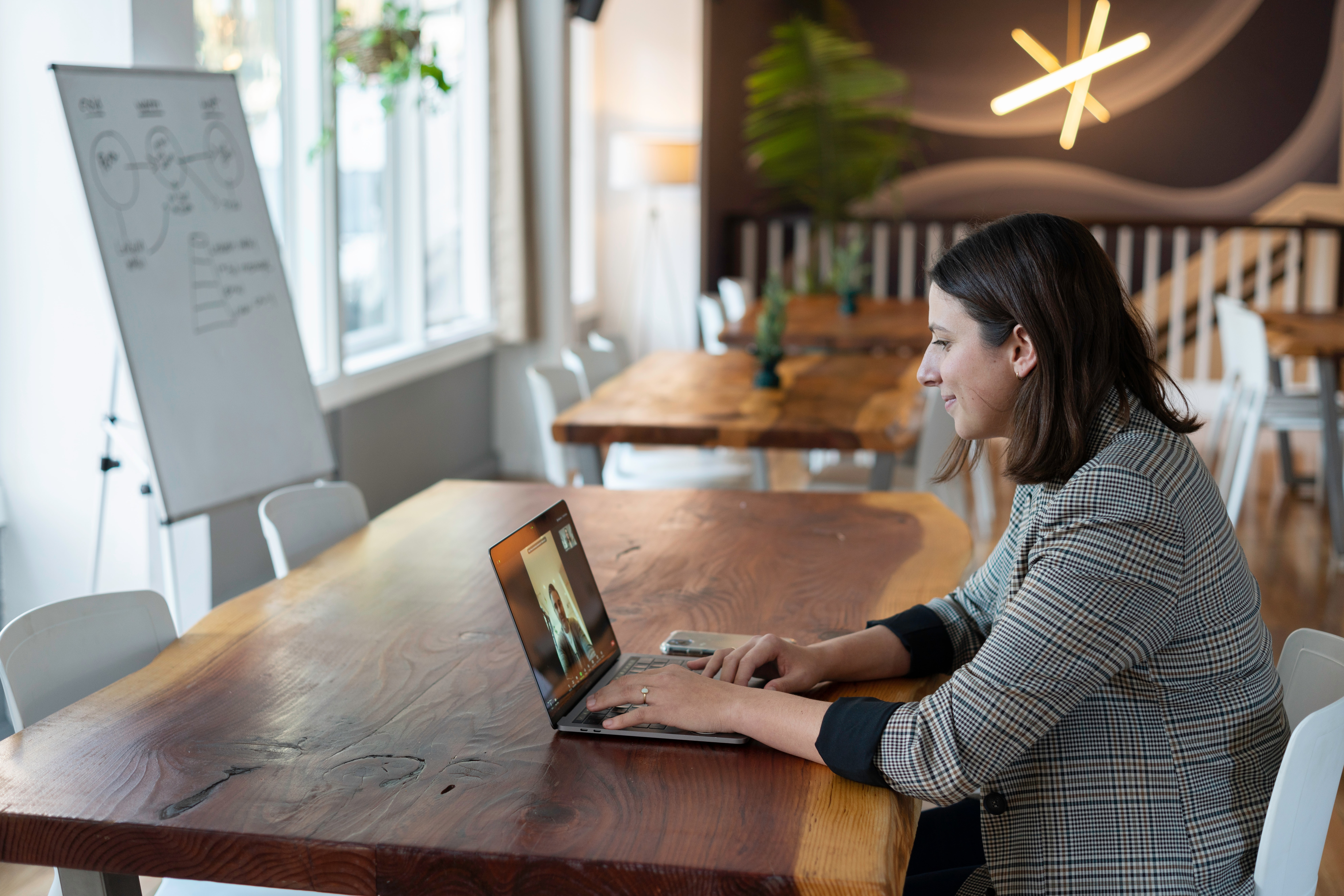 Woman sitting at a desk on a conference call with a whiteboard in the background