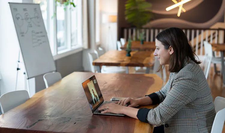 Woman sitting at a desk on a conference call with a whiteboard in the background