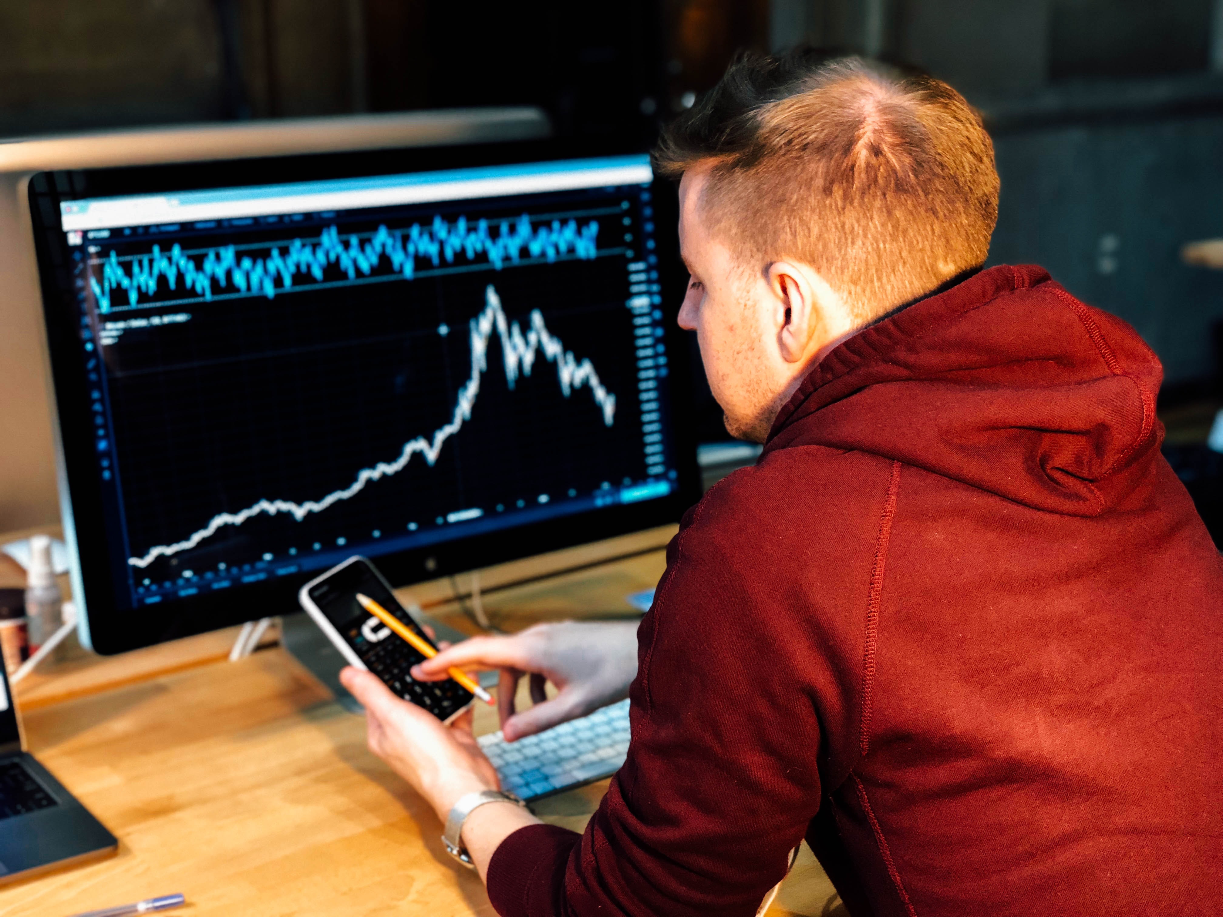A man sitting at a desk with a graph on his monitor