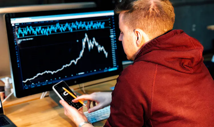 A man sitting at a desk with a graph on his monitor