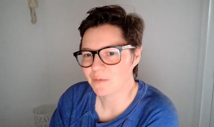 Woman with glasses sits in front of computer