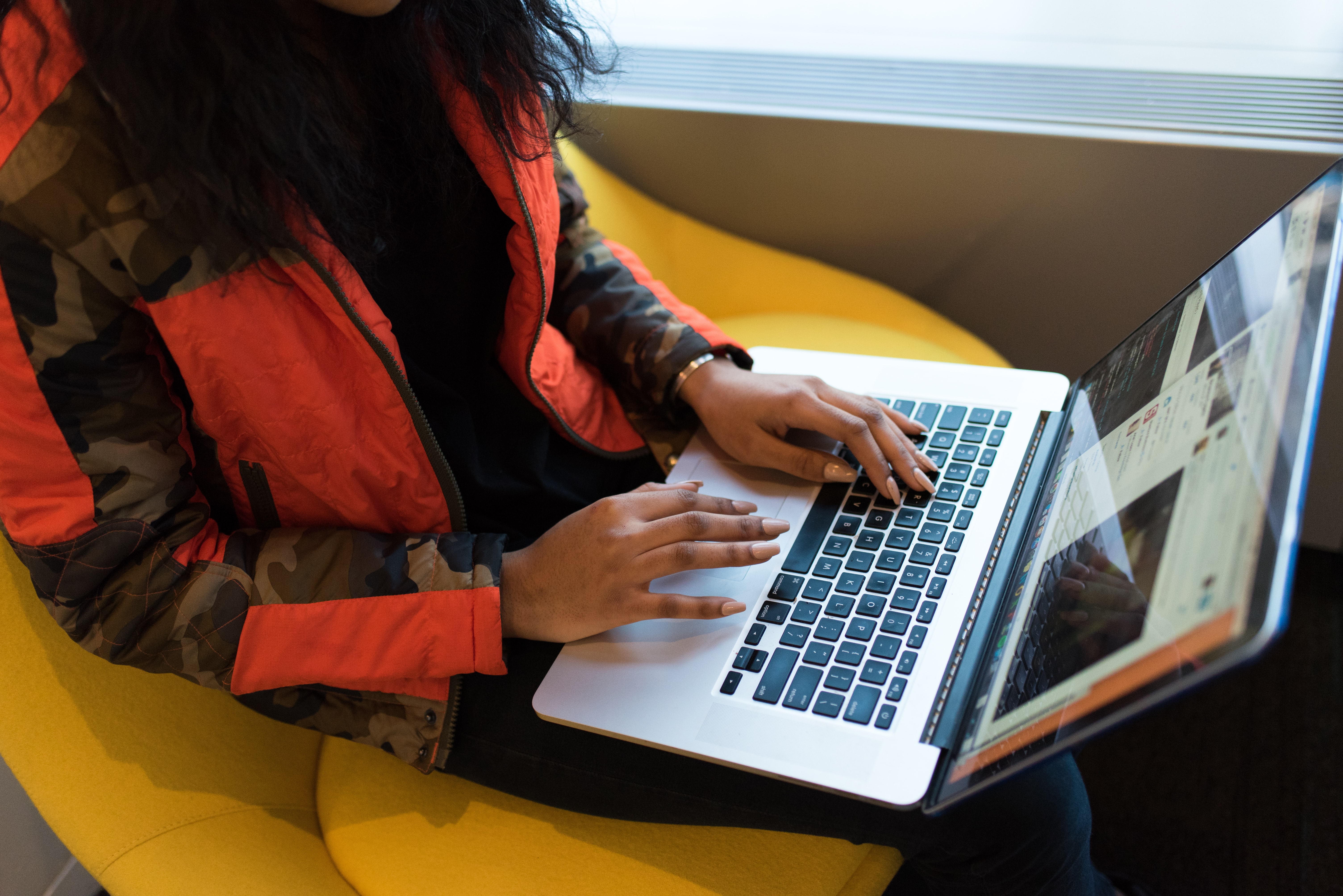 A woman sitting on a seat working on a laptop