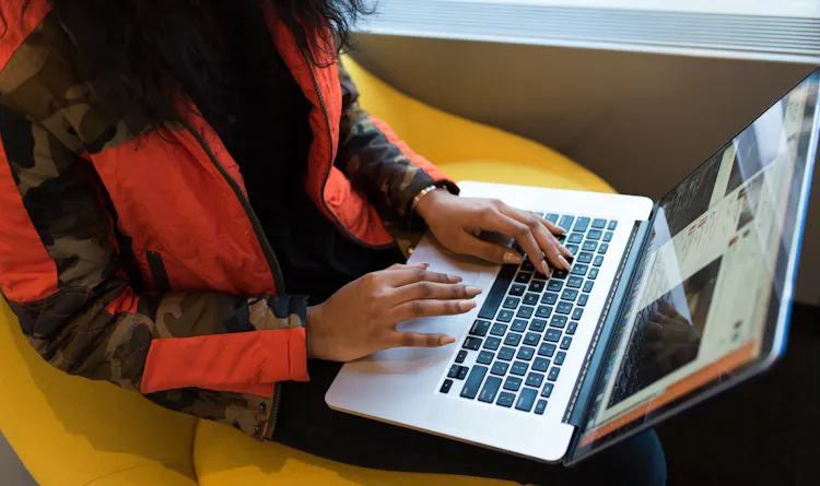 A woman sitting on a seat working on a laptop