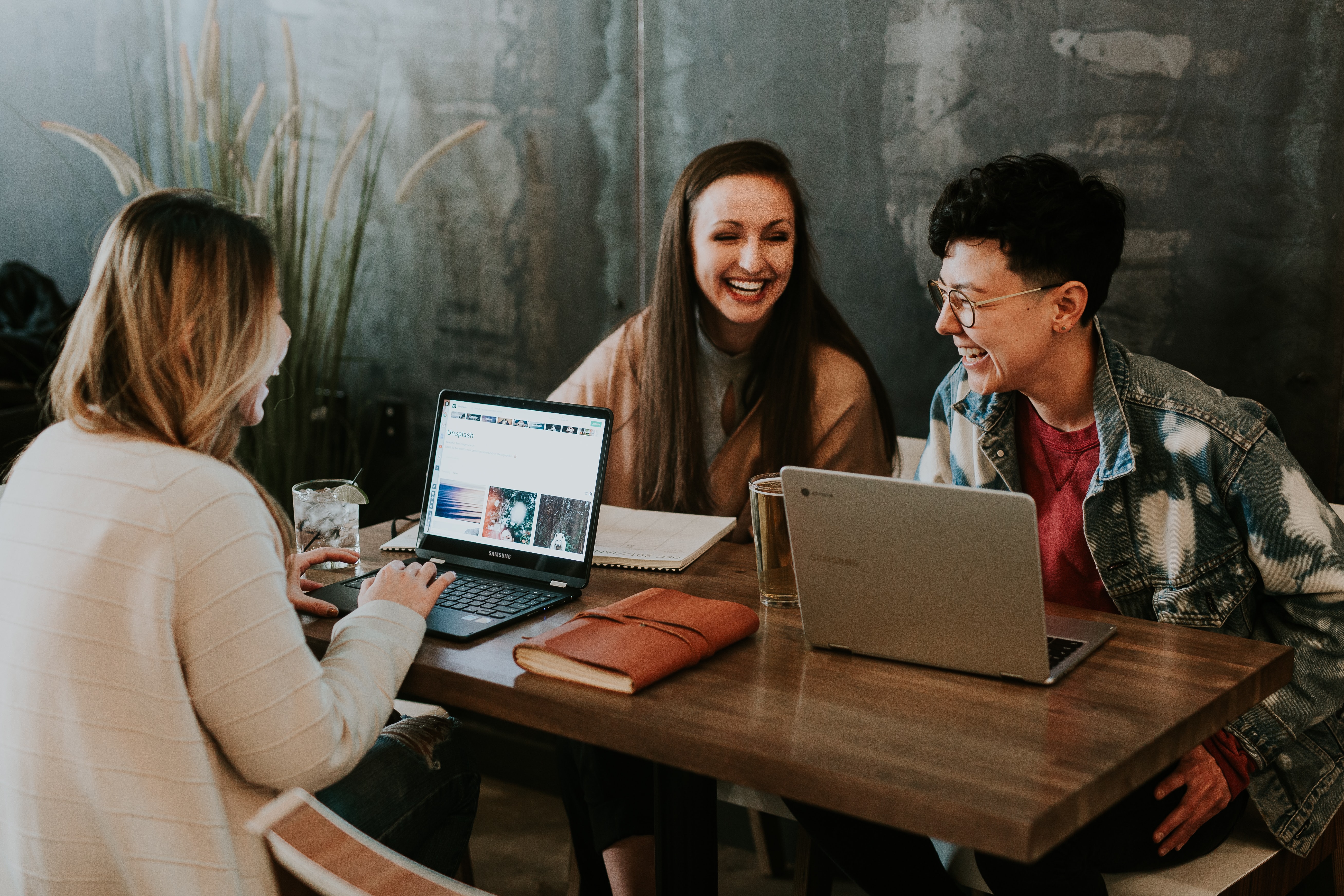 Three women sitting around a desk working on laptops
