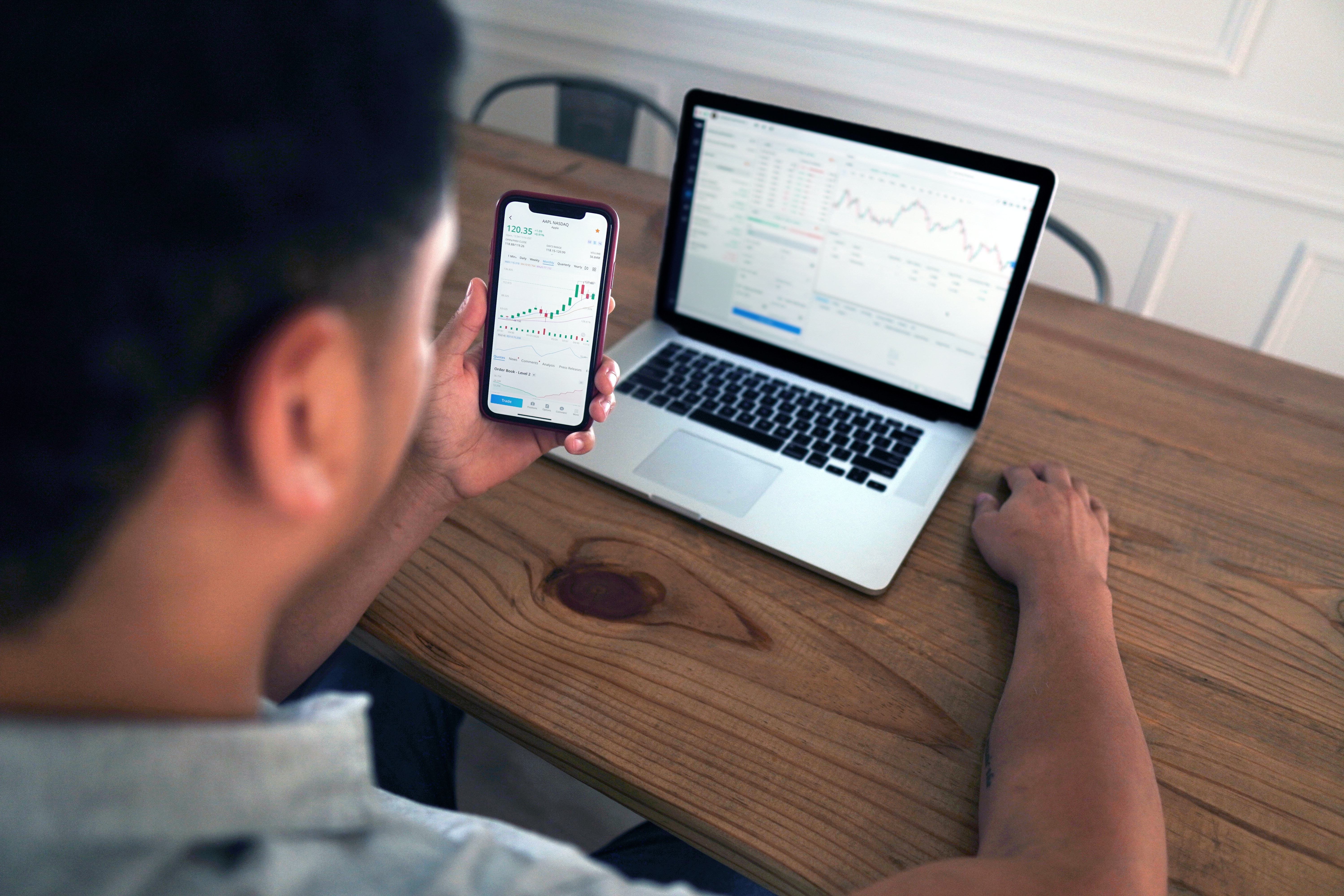 Cover of Man sitting at a desk looking at graphs on a laptop screen and a mobile device article