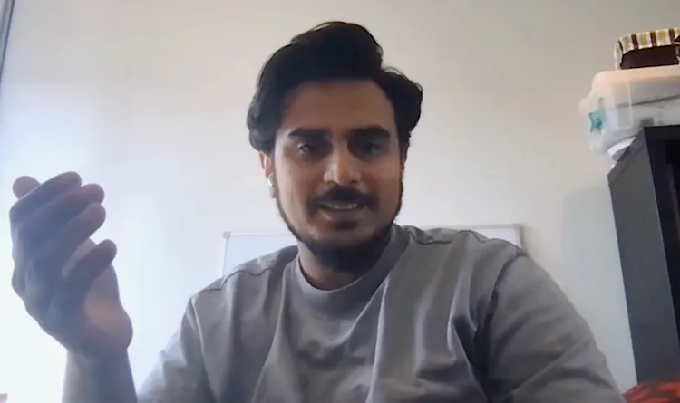 Man with earphones smiles in front of computer