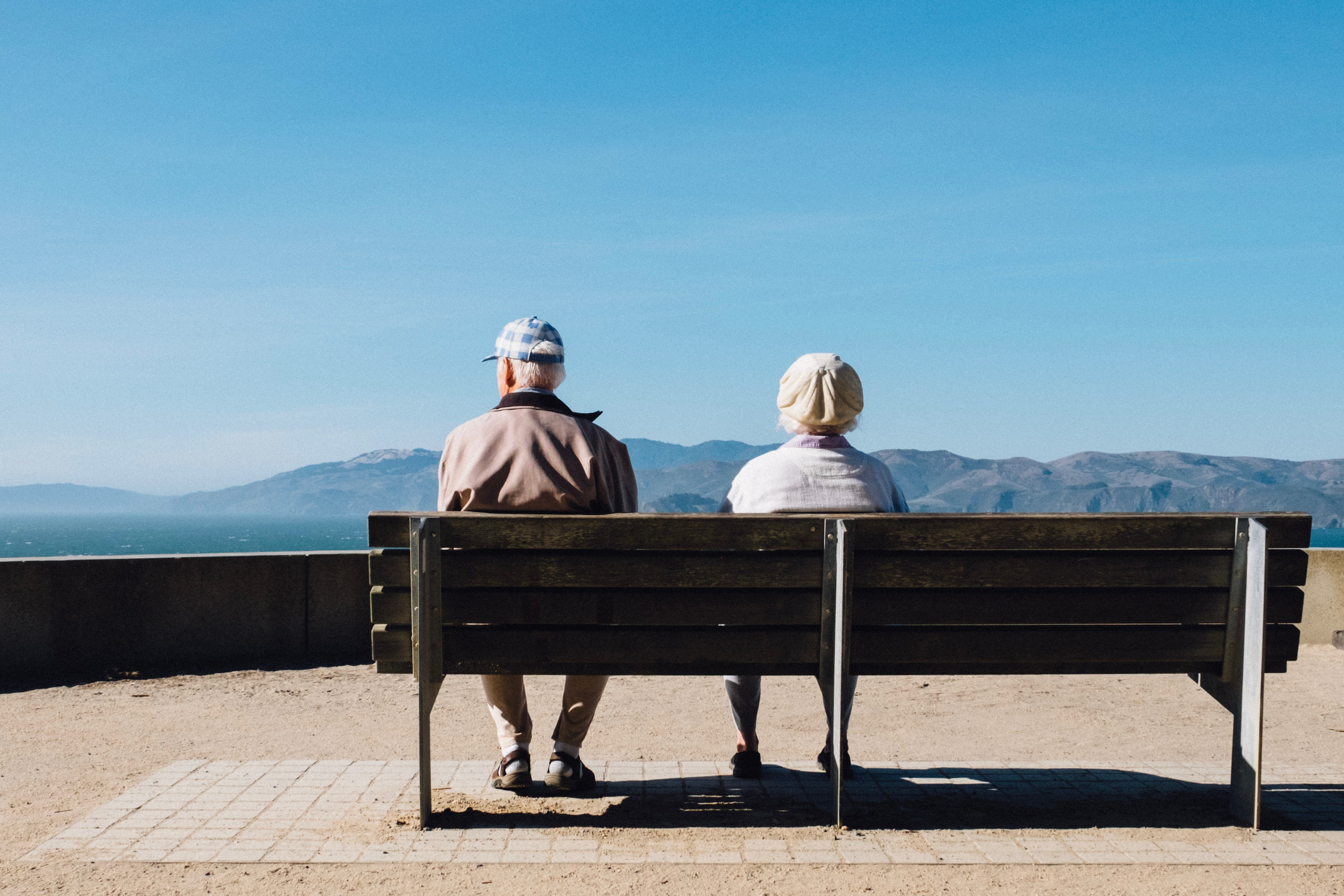 Two people sitting on a bench looking at mountains