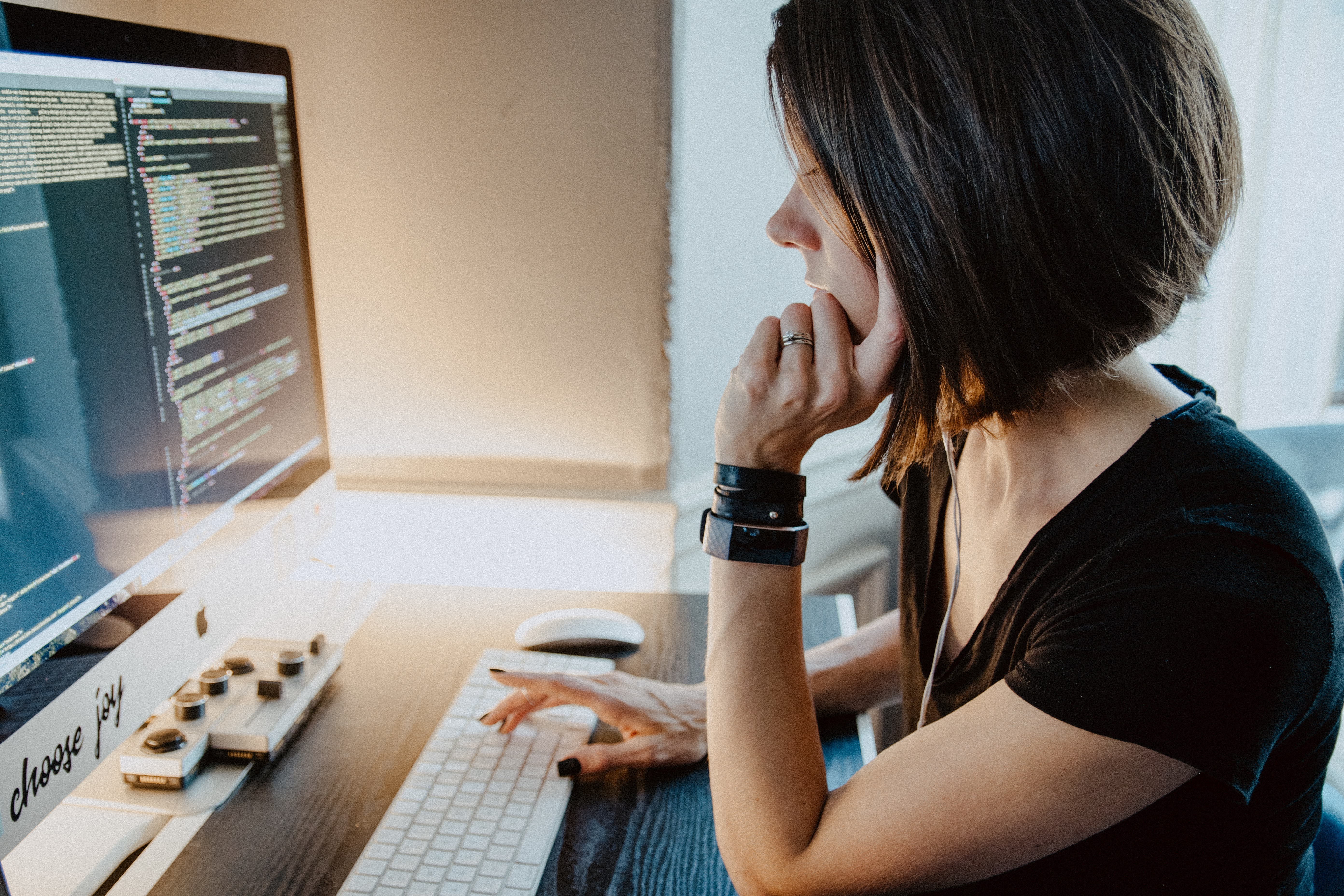 Woman sitting at a desk with code on the monitor