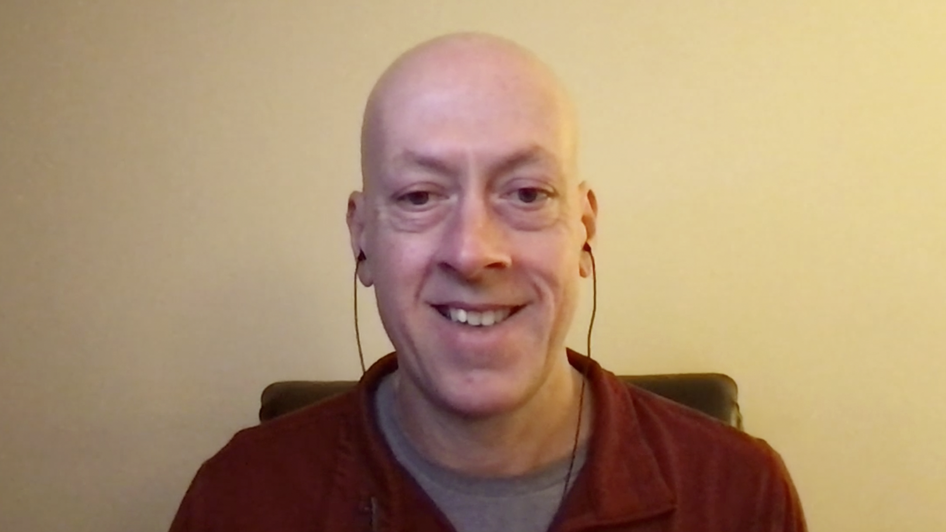 Man wearing earphones sits at computer