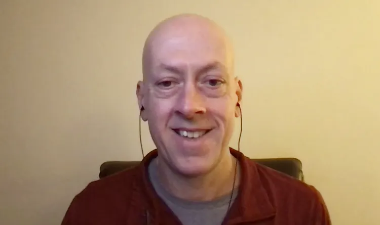 Man wearing earphones sits at computer