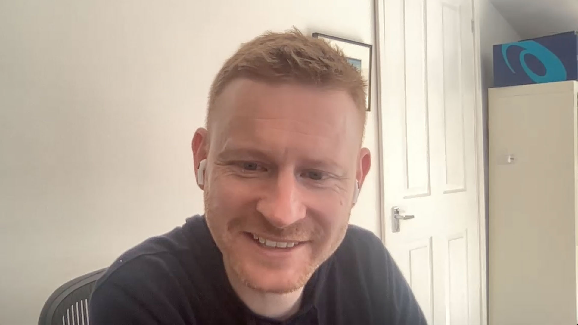 Smiling man sits in front of computer