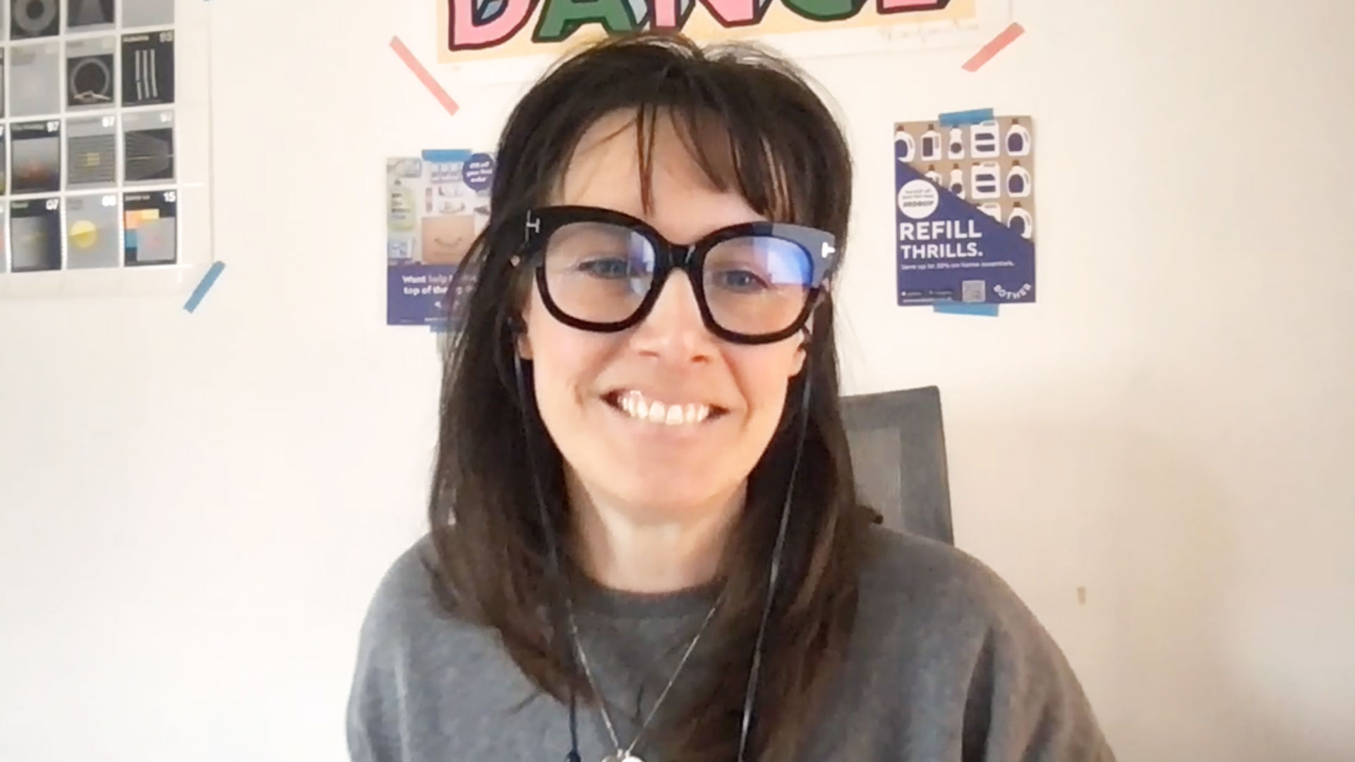 Smiling woman with glasses sits in front of computer