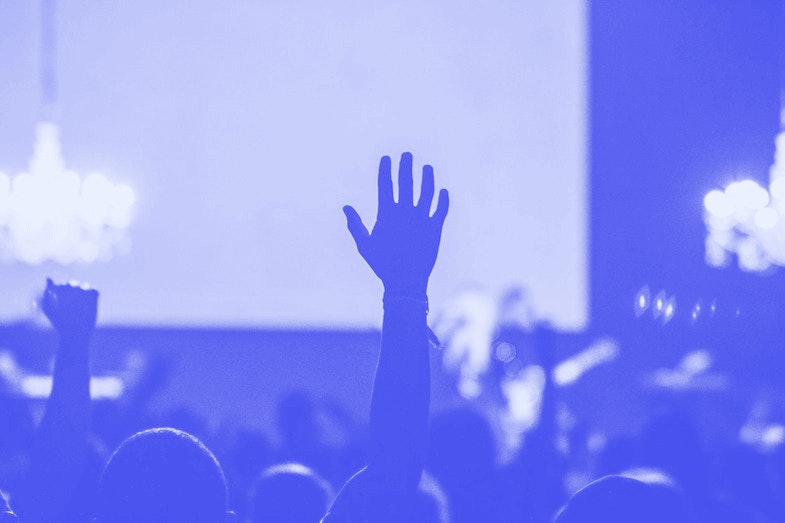 Person raising hand in crowd of people