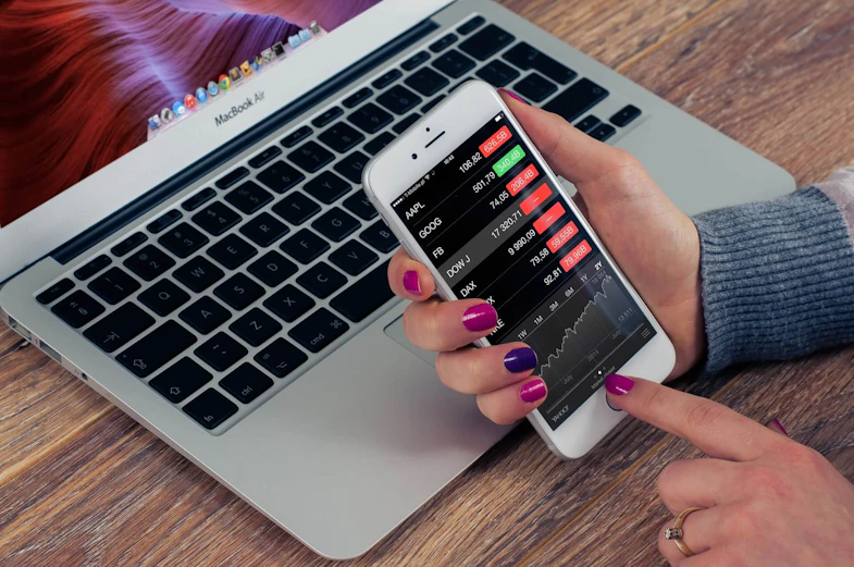laptop and mobile phone with investment information
