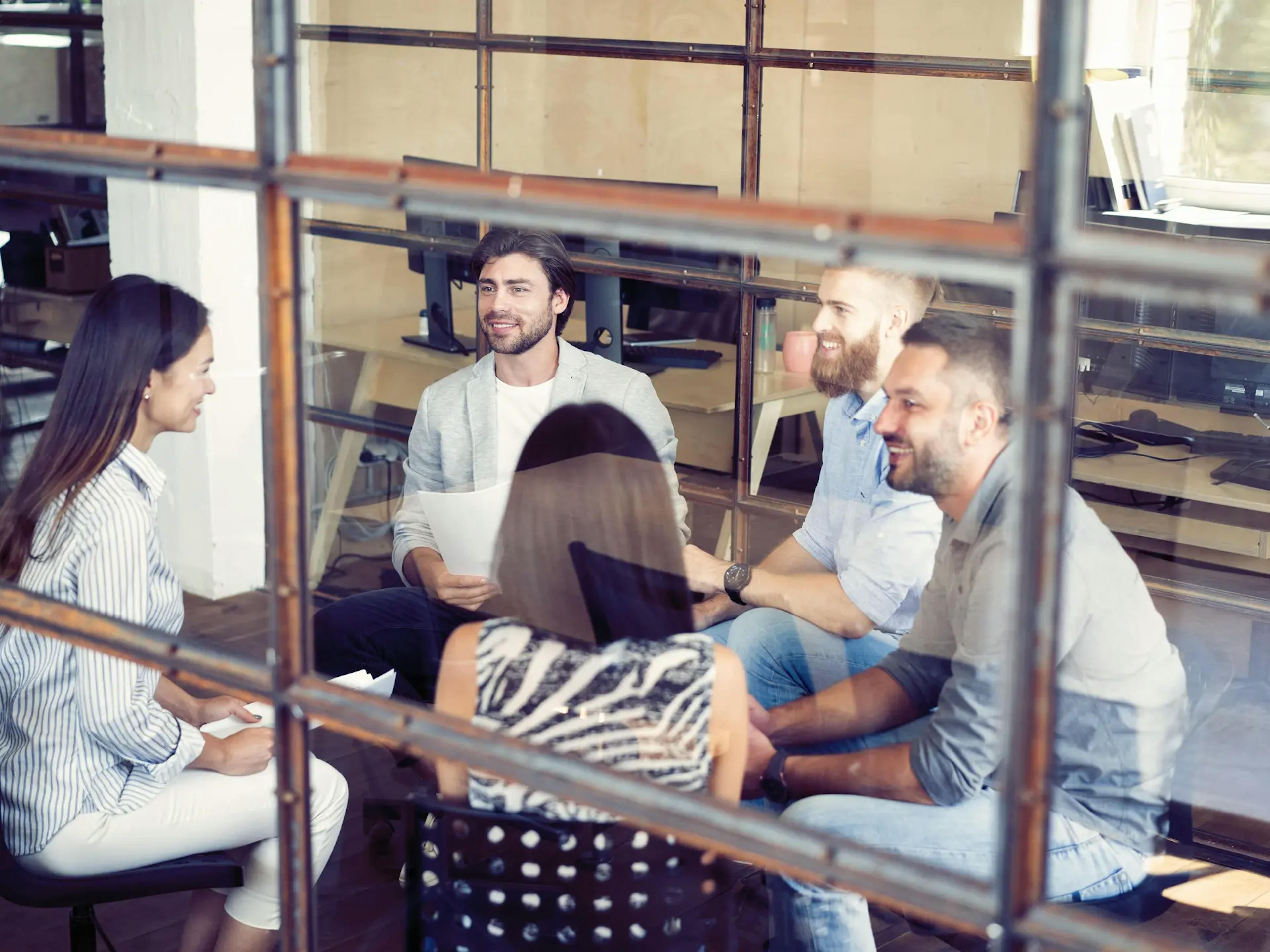 Group of professionals in discussion around a table, symbolizing partnership, collaboration, and shared goals in a modern workspace.