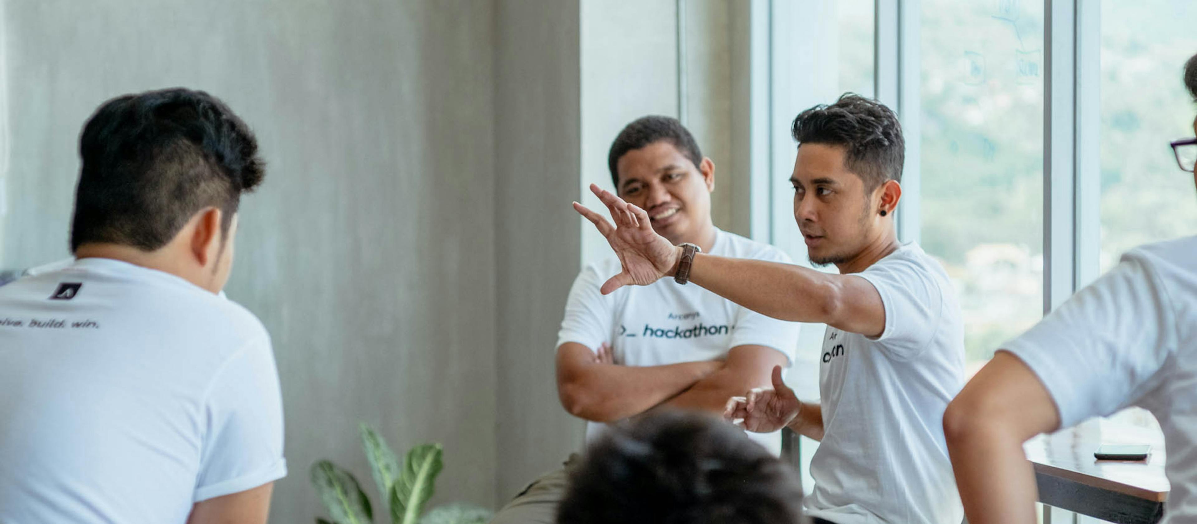 A group discussing with a person in the middle with their arms extended gesturing