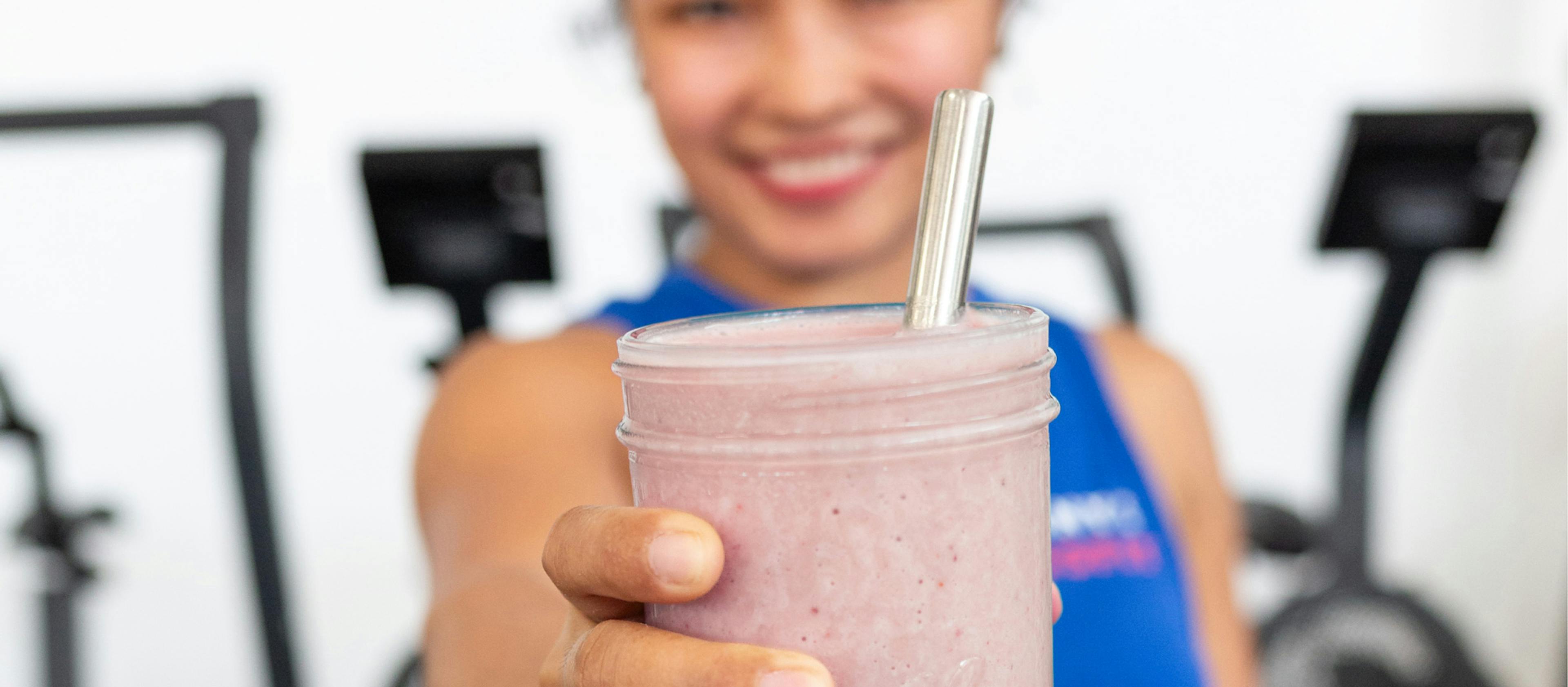 A close-up shot of a smoothie being held by a person in a gym