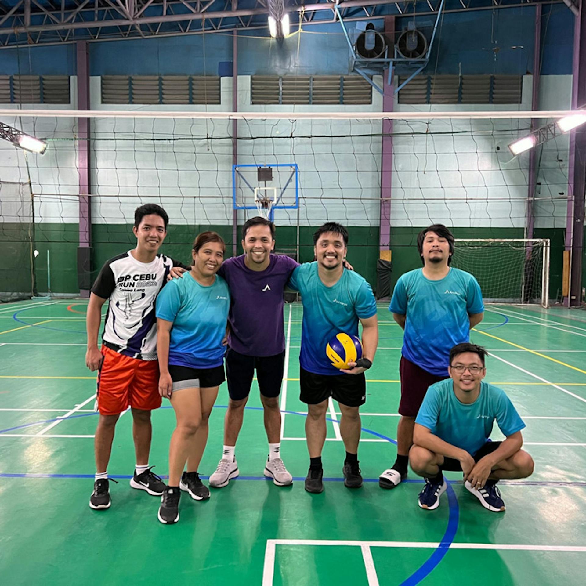 people posing in a gym with a volleyball tent