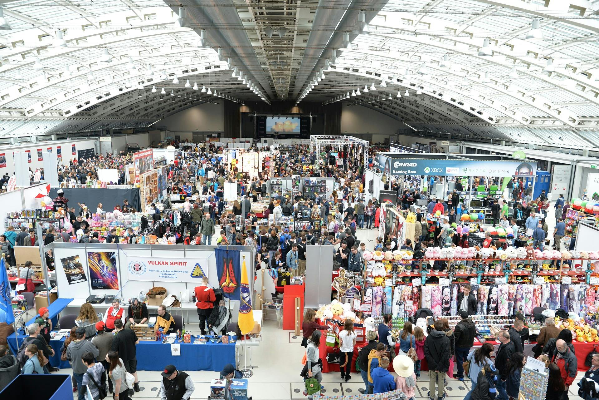 Comic convention with many stands and attendees.