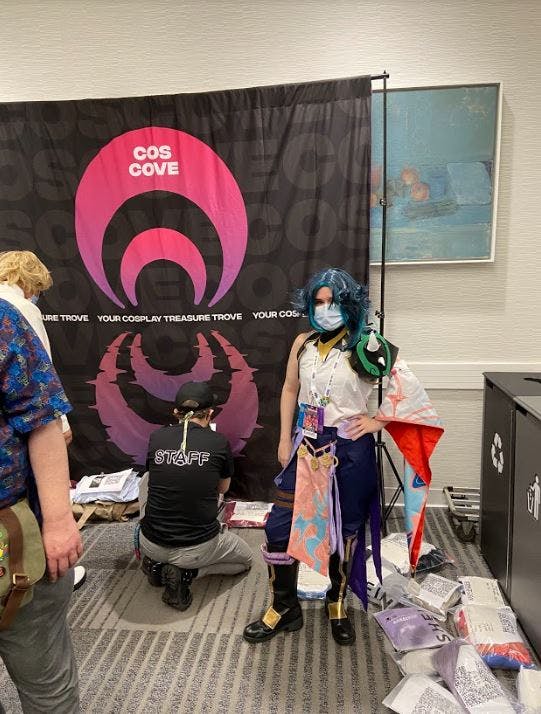 Genshin impact cosplayer posing with coscove sign at the in person cosplay market