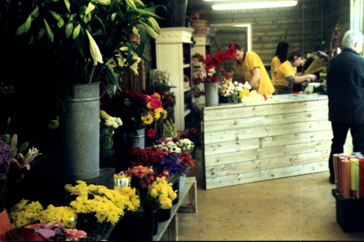 Plusieurs fleurs en pots et des vendeurs en fond