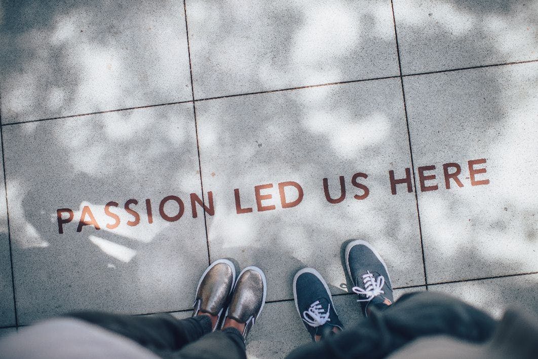 Employees stand on the sidewalk over a sign that says 'passion led us here'
