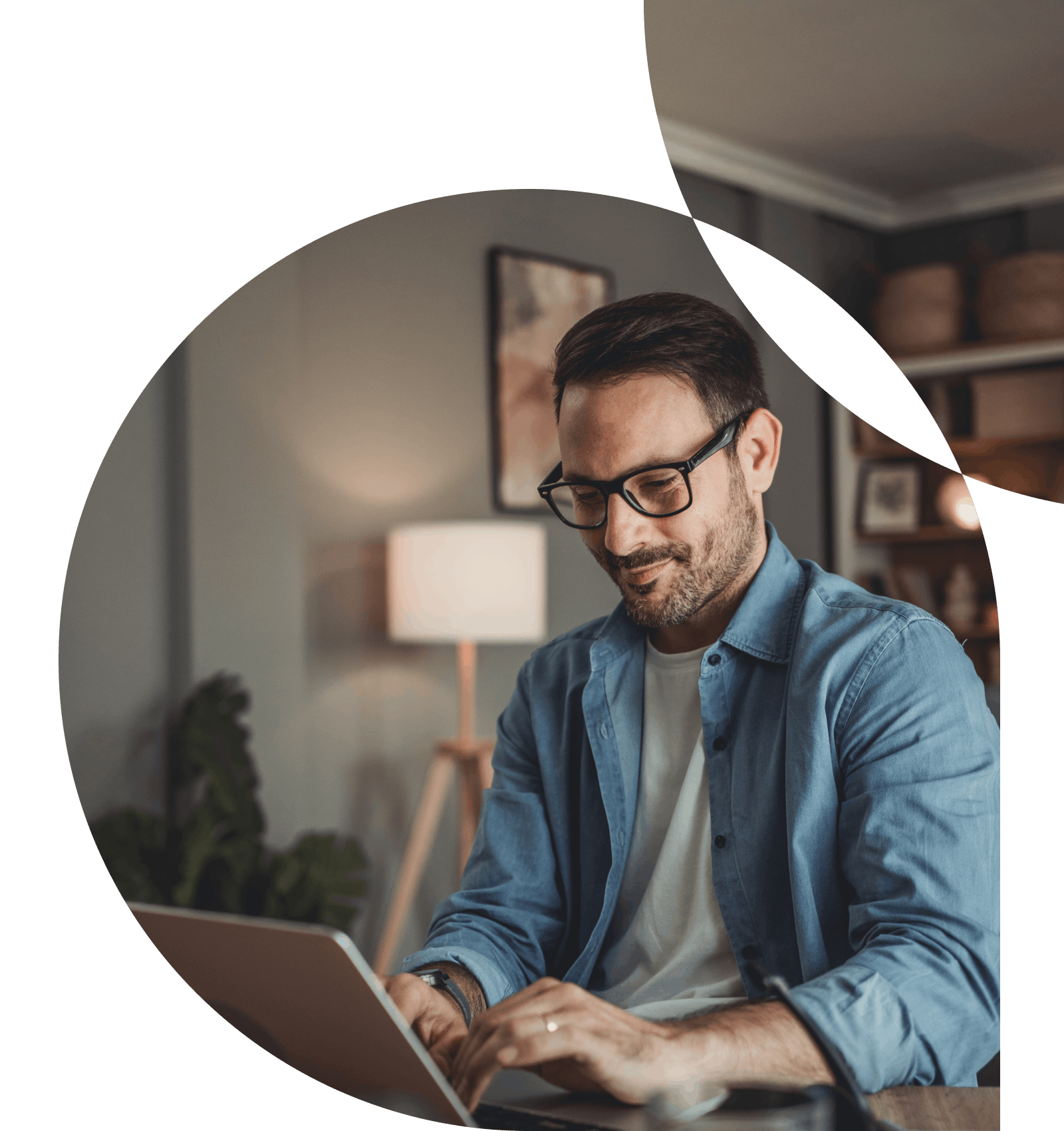 Man with glasses smiling while working on laptop