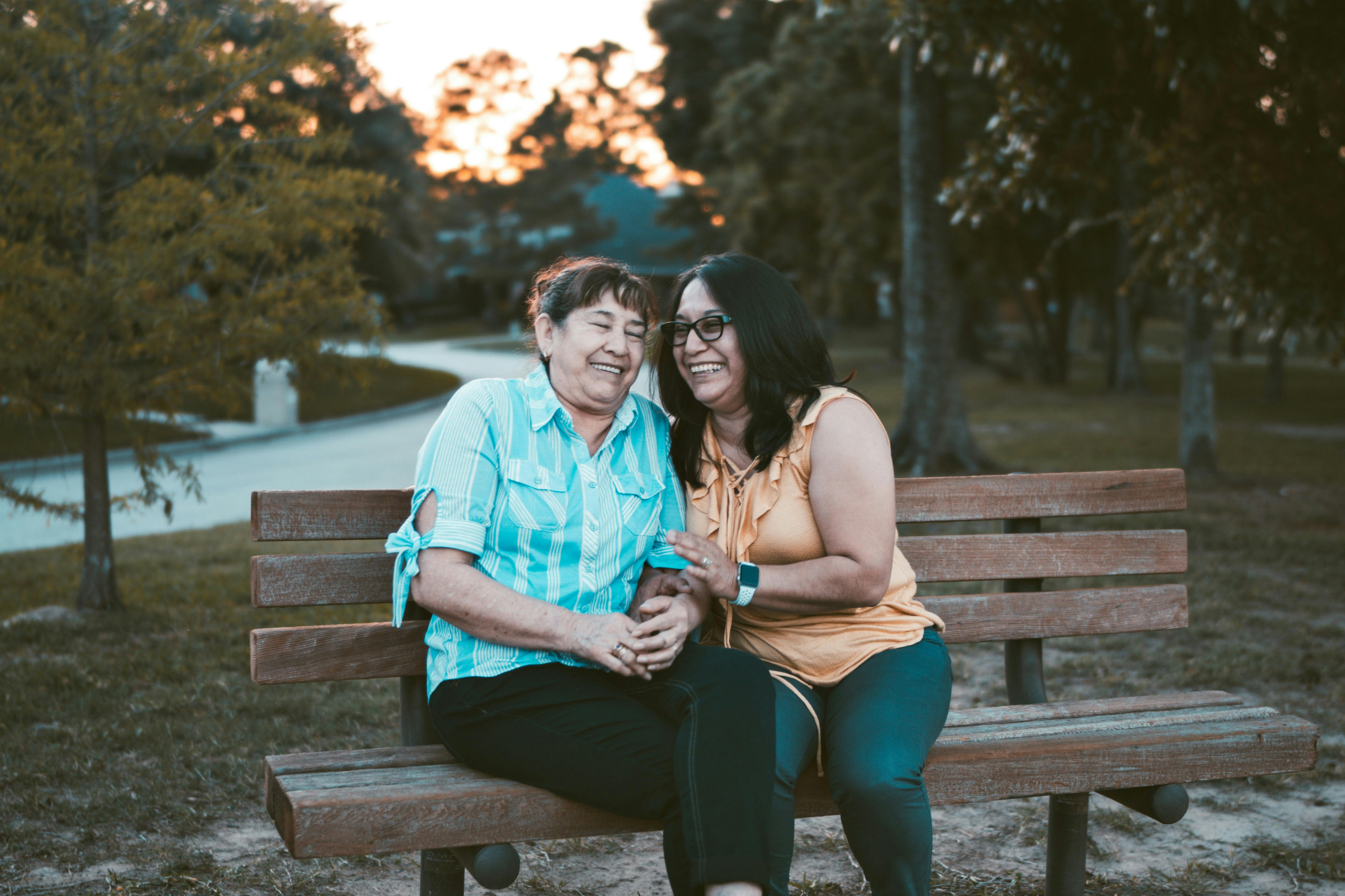 Two women sitting on a bench laughing together