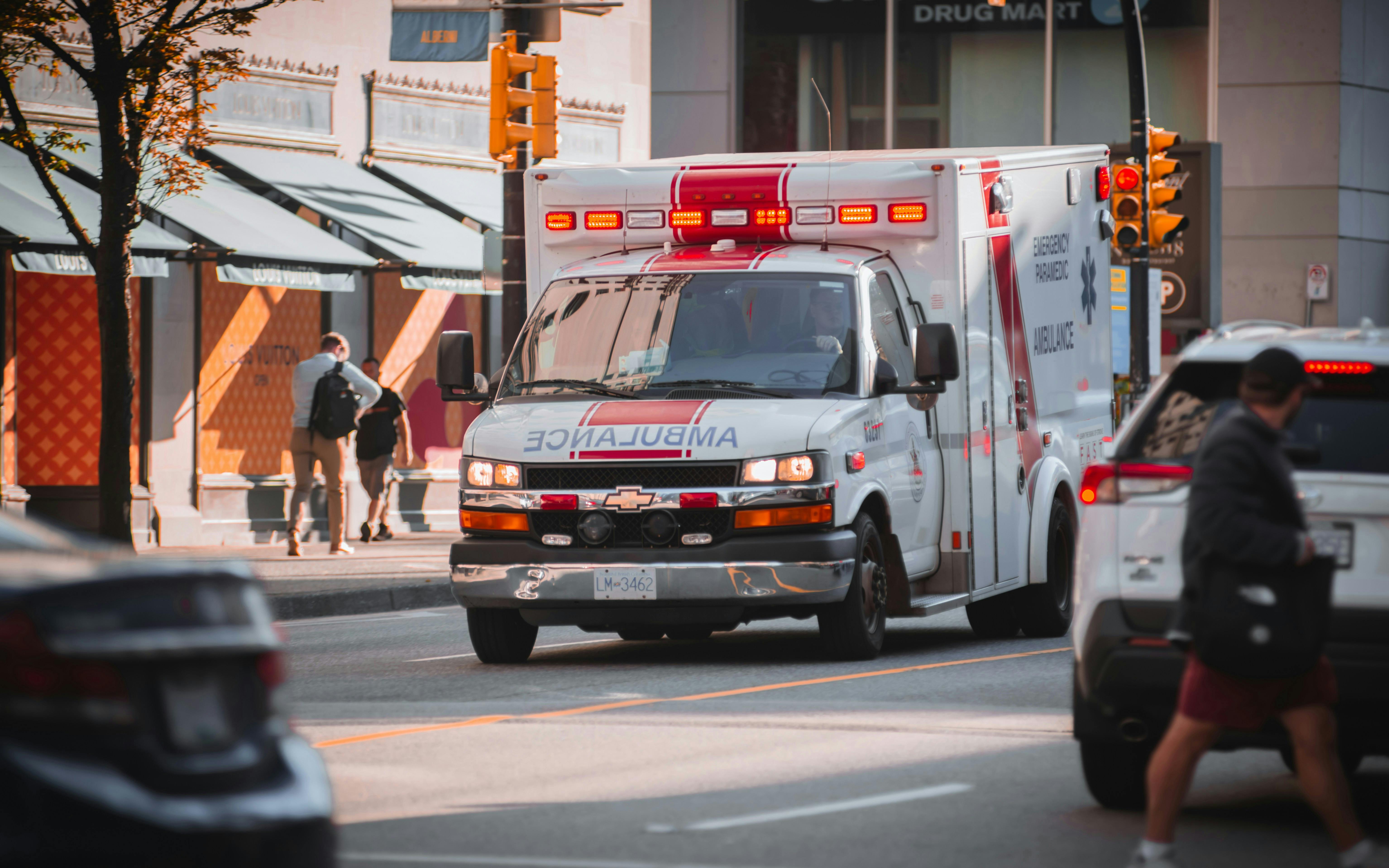 Ambulance driving down a city street with lights on