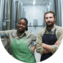 Two small business owners with insurance stand confidently on the manufacturing floor of their business
